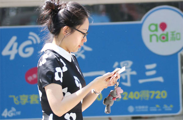 A woman checks her mobile phone in this file photo. China has the goal of connecting 400 million people to 4G networks by the end of the year. (Photo/China Daily)