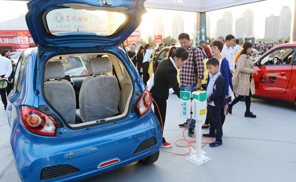 Visitors to an auto show check a charging post. The country is tightening its subsidy policies on new-energy vehicles in an attempt to transform the market from policy-driven.(Photo/China Daily)