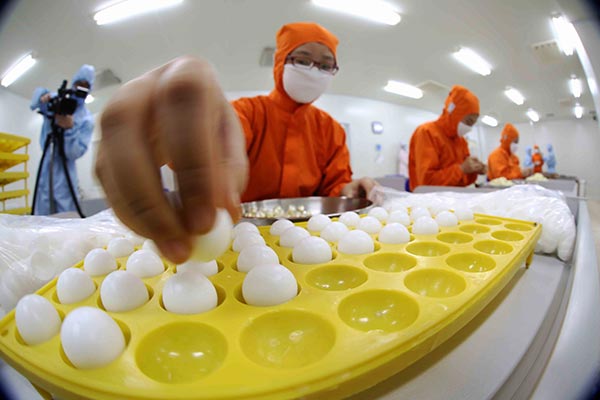 Employees arrange pills at a workshop owned by Beijing Tong Ren Tang Group Co Ltd, a traditional Chinese medicine maker.(Photo/Xinhua)