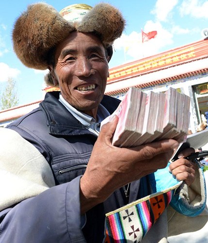 A farmer holds money he borrowed from a bank in Lhasa, Tibet autonomous region, in August.(Photo/Xinhua)