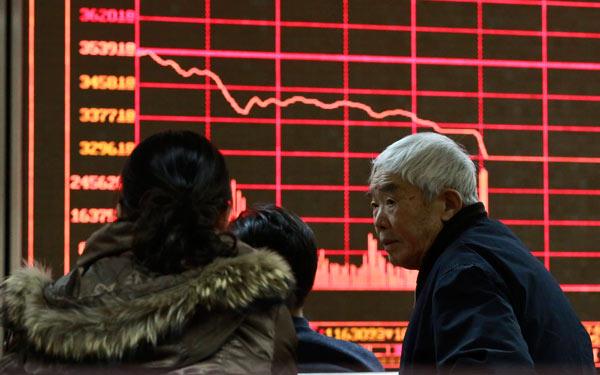 Residents monitor stock information in Beijing on Monday, when trading on China's stock markets closed around 1:30 pm after shares plunged, triggering the new circuit breaker. (Photo/China Daily)