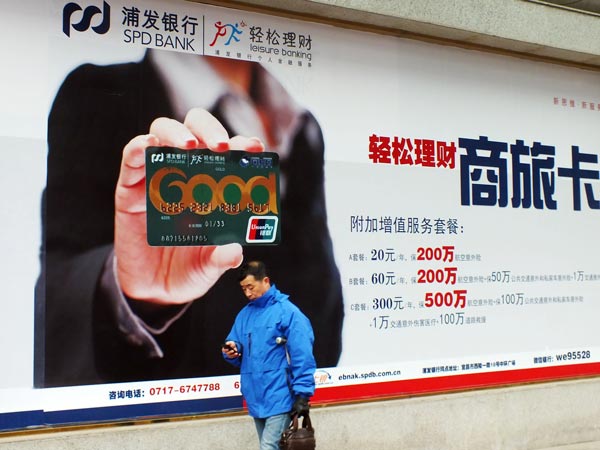A resident walks past an advertisement for Shanghai Pudong Development Bank Co Ltd in Yichang, Hubei province. The bank's assets reached 5.04 trillion yuan ($775.38 billion) by the end of 2015.(Photo/China Daily)
