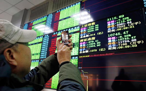 A man takes a photo of the trading screen at a securities brokerage in Shanghai on Thursday. (Photo/China Daily)