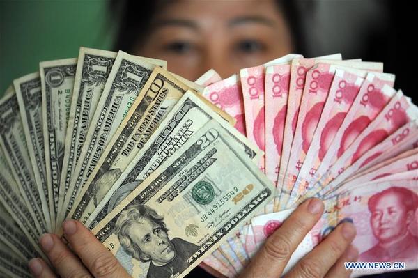 A resident shows China's RMB and U.S. dollar banknotes in Qionghai, south China's Hainan Province, Jan. 7, 2016. (Xinhua)
