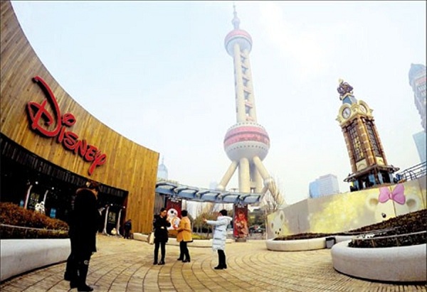 Tourists take pictures and chat in front of a Disney store in Shanghais Lujiazui financial district yesterday. Disneys long-awaited theme park in the citys Pudong New Area will open on June 16, the compamy announced yesterday. (Photo/Xinhua)