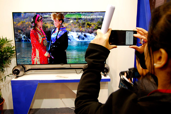 A woman takes a snapshot at the stand of Skyworth Digital Holdings Ltd during an industry expo in Wuhan, capital of Hubei province. (Photo/China Daily)