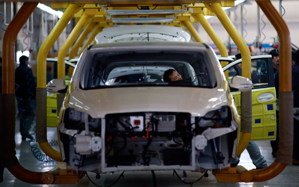 Employees assemble electric cars at a factory in Beijing. (Photo/China Daily)