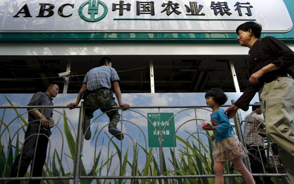 Pedestrians walk past a branch of Agricultural Bank of China in Shanghai.(Photo/China Daily)