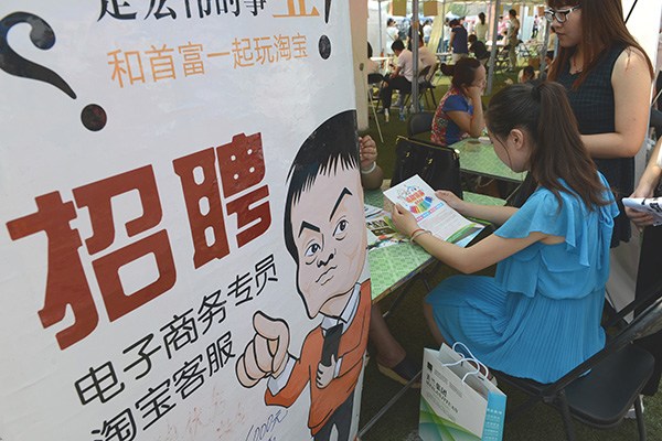 A woman graduate reads employment flier at an e-commerce job fair in Zhengzhou, Henan province, last May. (Photo/China Daily)