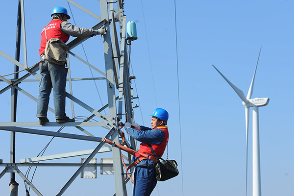 Workers check the transmission equipment at a wind power farm in Chuzhou, Anhui province. (Photo/China Daily)