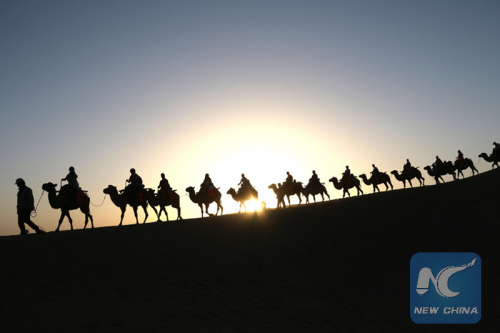 Visitors ride on camels in desert in Yueyaquan Scenic Spot in Dunhuang City, northwest China's Gansu Province, Aug. 8, 2015. (Photo: Xinhua/Zhang Xiaoliang)