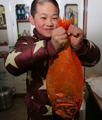 At his family home in Luochuan, Shaanxi province, Sun Caiyu shows off the New Zealand fish bought online. His family bought several foreign food items online for this year's traditional Spring Festival banquet at his home. (Photo provided to China Daily)