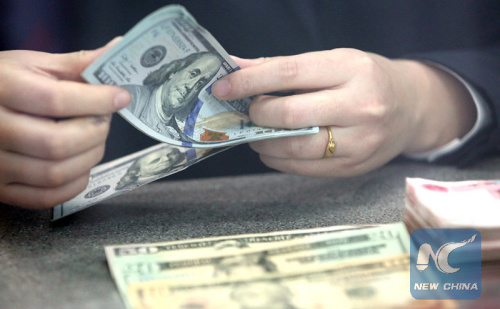 A bank staff member counts U.S. dollar banknotes at a bank in Tancheng County of Linyi City, east China's Shandong Province, Jan. 7, 2016. (Photo: Xinhua/Zhang Chunlei)