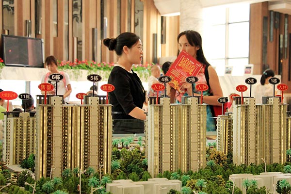 Potential customers look at a model of a real estate development in Haikou, Hainan province, Oct 18, 2015.(Shi Yan /for China Daily)