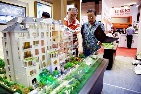 Visitors check out a model of an apartment building at a real estate show in Beijing.(Photo/Xinhua)