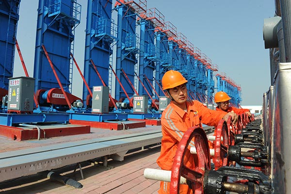 Workers check facilities at the Shengli Oilfield near Dongying, Shandong province. The oil producer is to shut down four oilfields to reduce costs amid plummeting oil prices. (HU QINGMING / FOR CHINA DAILY)