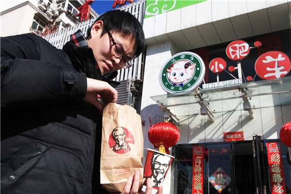 A man carries his Kentucky Fried Chicken lunch in front of a Little Sheep outlet in Tianjin. The boom-and-bust of Little Sheep Mongolian Hot Pot proves the process of going global is not always cheerful.(Photo provided to China Daily)