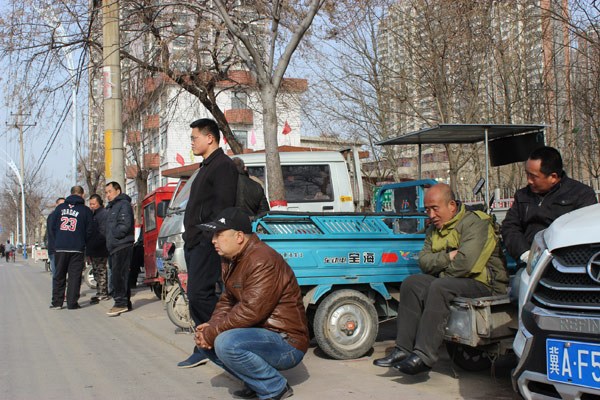 Farmers wait for their potential employers at a roadside labor market in Shijiazhuang, Hebei province. (Photo by Zhang Yu/chinadaily.com.cn)