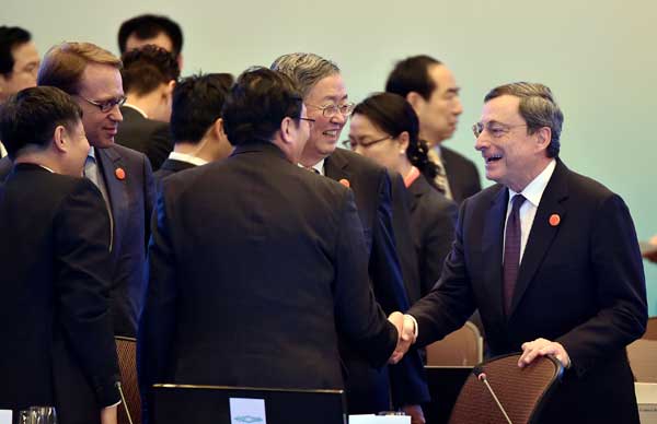 Mario Draghi (right), president of the European Central Bank, shakes hands with Finance Minister Lou Jiwei as People's Bank of China Governor Zhou Xiaochuan looks on before the opening ceremony of the G20 Finance Ministers and Central Bank Governors Meeting on Friday in Shanghai. LI XIN / XINHUA