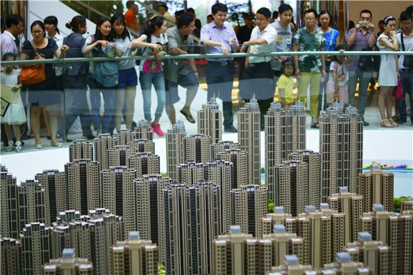 Potential homebuyers examine a property model in Yichang, Hubei province. China's housing market continued an upward trend in January, with more than half of major cities reporting month-on-month rises in new-home prices. ZHOU JIANPING/CHINA DAILY