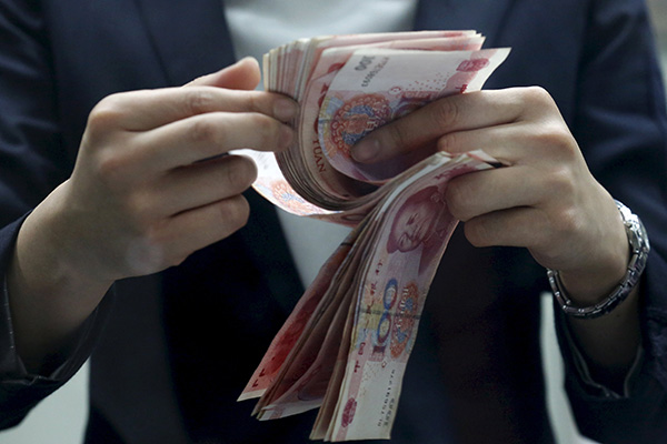 A clerk counts Chinese 100 yuan banknotes at a branch of a foreign bank in Beijing Jan 4, 2016. [(Photo/Agencies)