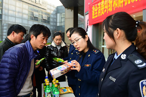 Staff with the local administration for industry and commerce in Hefei, capital of Anhui province, teach consumers how to tell fake products from genuine ones. (Photo/Xinhua)