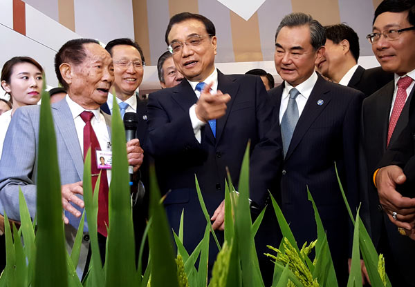 Premier Li Keqiang consults with Yuan Longping (left), known as the father of hybrid rice, during an exhibition on Lancang-Mekong cooperation in Sanya, Hainan province, on Wednesday. WU ZHIYI / CHINA DAILY