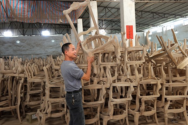 A worker carries an unpainted chair in a furniture factory in Dongguan, Guangdong province. The traditional Chinese-style furniture is mainly for export. (Photo provided to China Daily)