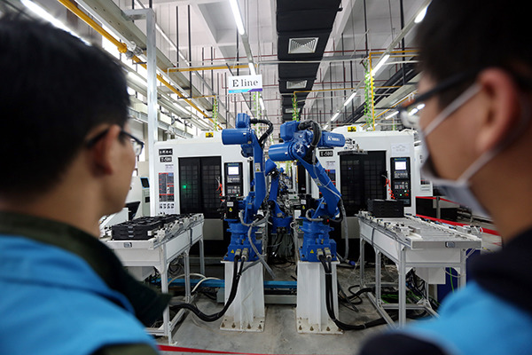 Two workers inspect a production line equipped with robots in Dongguan. (Photo/China Daily)