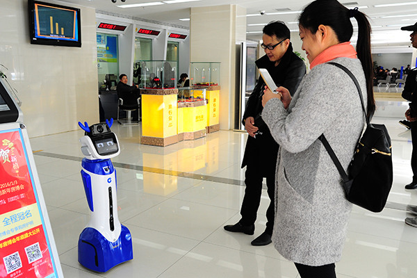 A robot in a bank in Taicang, Jiangsu province, attracts customers' attention. To survive fierce competition, many lenders have opted to upgrade their services. (Photo/China Daily)