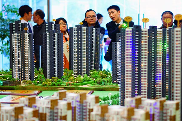 Potential customers look at a model of a real estate development in Yichang, Hubei province.(ZHOU JIANPING / FOR CHINA DAILY)
