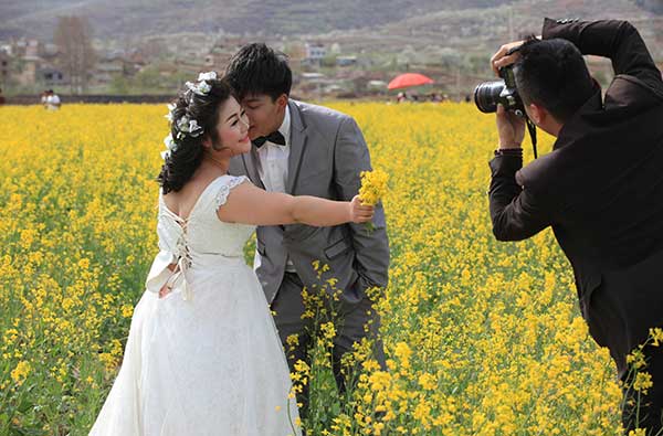 A newlywed couple has their picture taken in a rapeseed field in Zhaotong city, Yunnan province.Zhang Guangyu / For China Daily