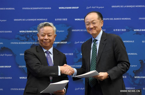 World Bank President Jim Yong Kim (R) and Asian Infrastructure Investment Bank (AIIB) President Jin Liqun shake hands after signing the first co-financing framework agreement at the headquarters of World Bank in Washington D.C., the United States, April 13, 2016. World Bank and the AIIB on Wednesday signed the first co-financing framework agreement, paving the way for their cooperation on joint projects this year. (Photo: Xinhua/Yin Bogu)