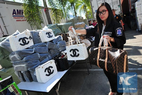 A Thai customs official holds handbags with fake brand names at Thai Customs headquarters in Bangkok, Thailand, Jan 16, 2015.Photo/Xinhua