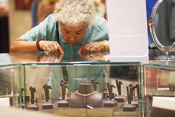 A customer chooses gold jewelry at a store in Beijing. CAO BOYUAN / FOR CHINA DAILY