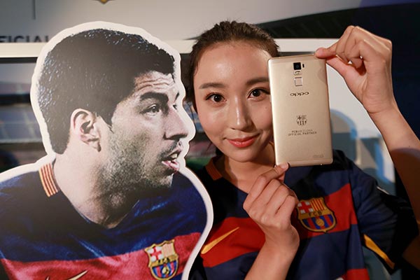 A model displays an Oppo brand mobile phone that carries the logo of FC Barcelona in Beijing. Oppo is targeting younger customers not only in China, but also in emerging markets worldwide.(Photo/Xinhua)