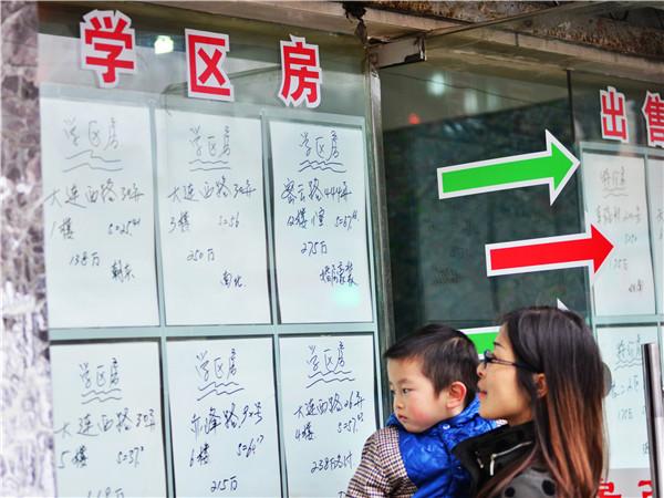 A mother and her son look at advertizements for school area houses in Dalian, Liaoning province.SHEN XUECHEN/CHINA DAILY