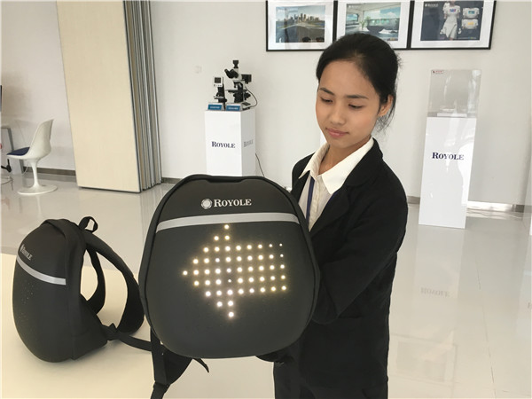 A staff member illustrates a smart backpack that uses flexible sensors developed by Royole Corp.(WANG ZHENGHUA/CHINA DAILY)