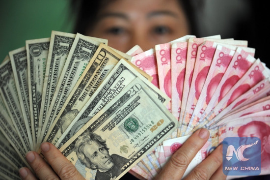 A residents shows China's RMB and US dollar banknotes in Qionghai, south China's Hainan Province, Jan. 7, 2016. (File photo: Xinhua/Meng Zhongde) 