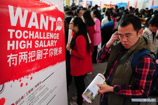 A job seeker looks through employment information at a job fair held for fresh graduates in Liaocheng city, East China's Shandong province, March 14, 2015. (Photo/Xinhua)