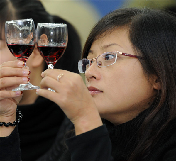 A woman takes a close look at two imported wines during a wine-tasting event in Ningbo, Zhejiang province.(CHINA DAILY)