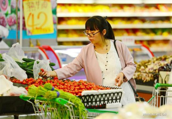 A woman chooses vegetables inside a supermarket in Baoding City, north China's Hebei Province, April 10, 2016. (Photo: Xinhua/Zhu Xudong)