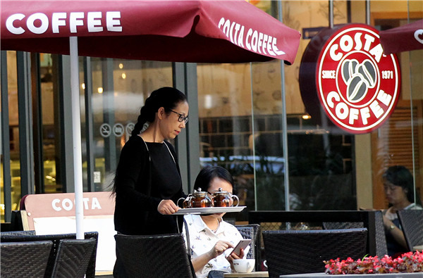 A waitress serves beverages to customers at a Costa cafe in Chaoyang District, Beijing.(ZHANG WEI/CHINA DAILY)