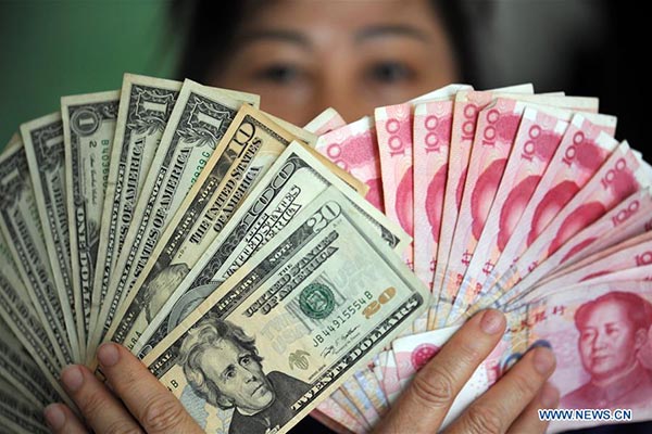 A residents shows China's yuan and U.S. dollar banknotes in Qionghai, South China's Hainan province, Jan 7, 2016. (Photo/Xinhua)
