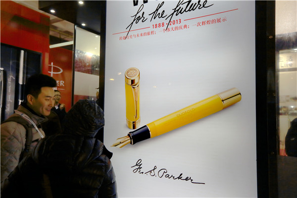 Two visitors stand in front of the Parker pen's billboard at an international gift fair in Beijing.A QING/CHINA DAILY