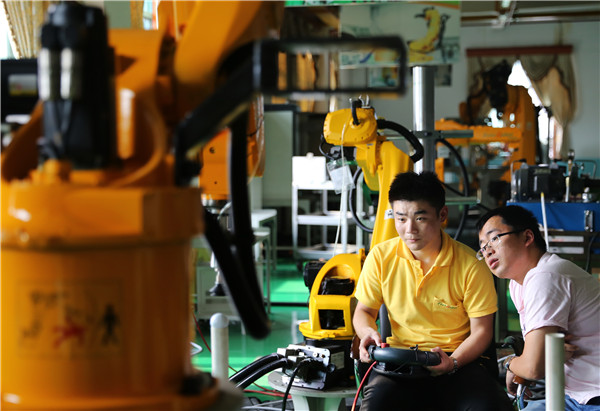 A technician commands an industrial robot at the workshop of Ruihong Robot Ltd in Jiaxing, Zhejiang province.THOMAS WEI/CHINA DAILY