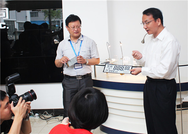 Chen Yu (right), CEO of Guangzhou OED Technologies, shows a price tag made of graphene e-paper. CHINA DAILY