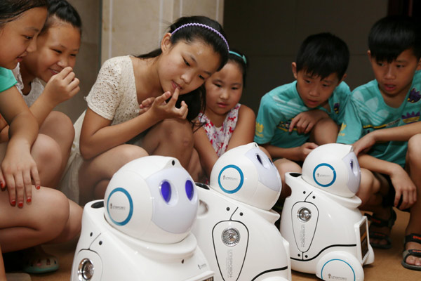Students watch intelligent robots developed by a Beijing company for use in education, elderly care, household chores and security purposes. (Photo / Provided to China Daily)