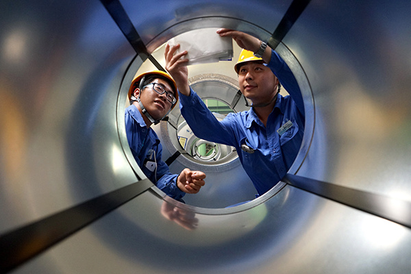Two workers stick production identifications on steel products at a cold rolling mill of Tangsteel Group Ltd in Tangshan, Hebei province.(Photo/China Daily)