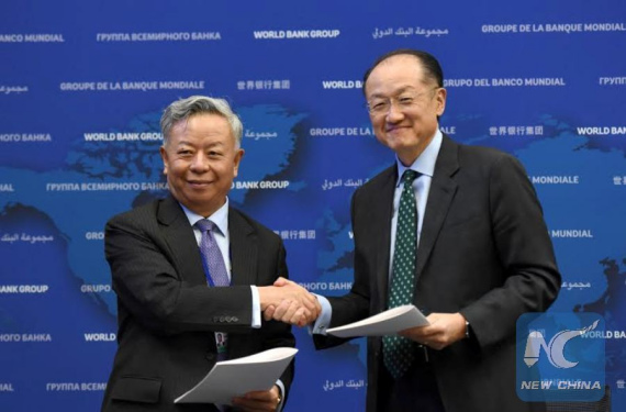 World Bank Group President Jim Yong Kim (R) and Asian Infrastructure Investment Bank(AIIB) President Jin Liqun shake hands after signing the first co-financing framework agreement at the headquarters of World Bank in Washington D.C., the United States, April 13, 2016. (Photo: Xinhau/Yin Bogu)